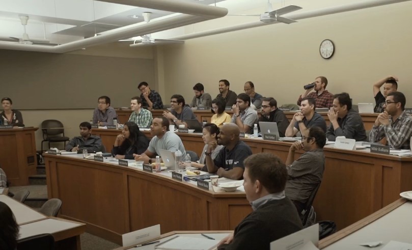 A group of diverse individuals seated around a conference table engaged in discussion