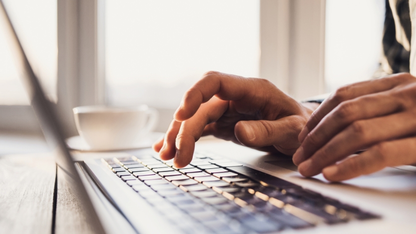 Close-up of a teacherโs hands typing on a laptop