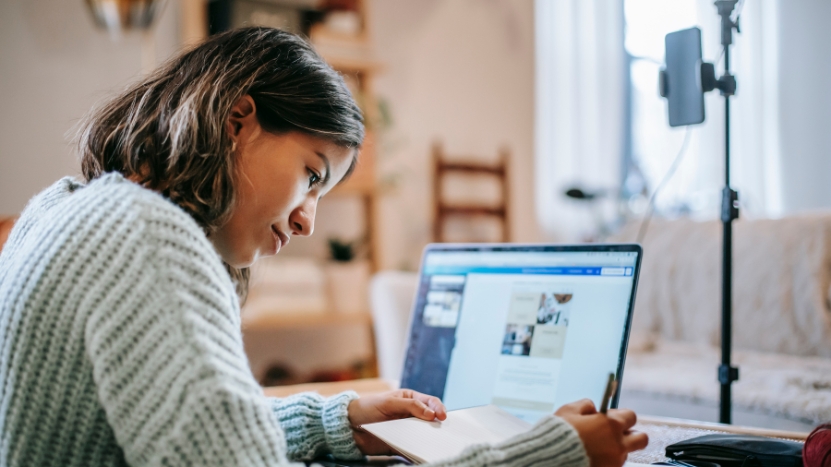 A student studies with a laptop and notebook, practicing active recall techniques