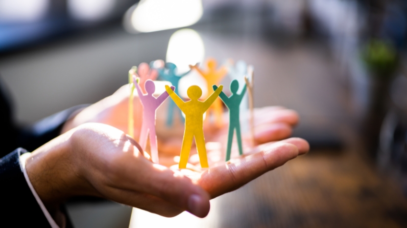 Hands hold paper cut-out figures forming a circle to represent a unified team