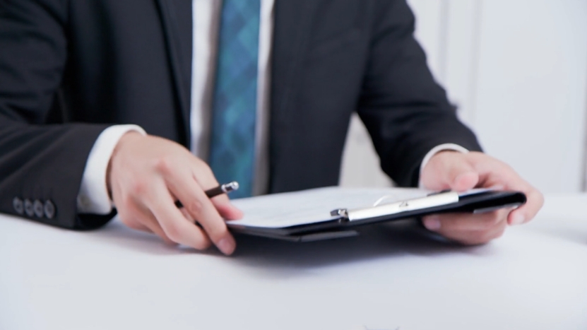 A business professional holds a clipboard during an executive hiring discussion