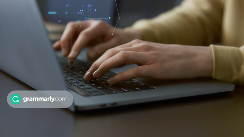 Hands Typing on A Laptop with The Grammarly Logo Displayed on The Screen