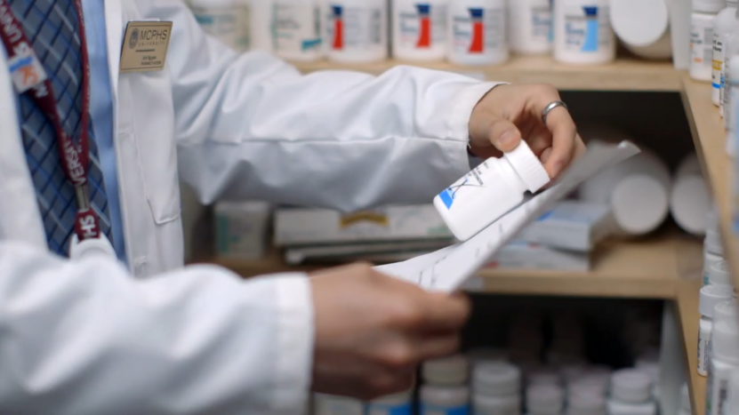 A Pharmacist Reviewing a Prescription While Holding a Medication Bottle in A Pharmacy