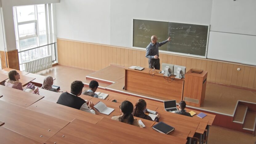 A professor stands in front of a blackboard